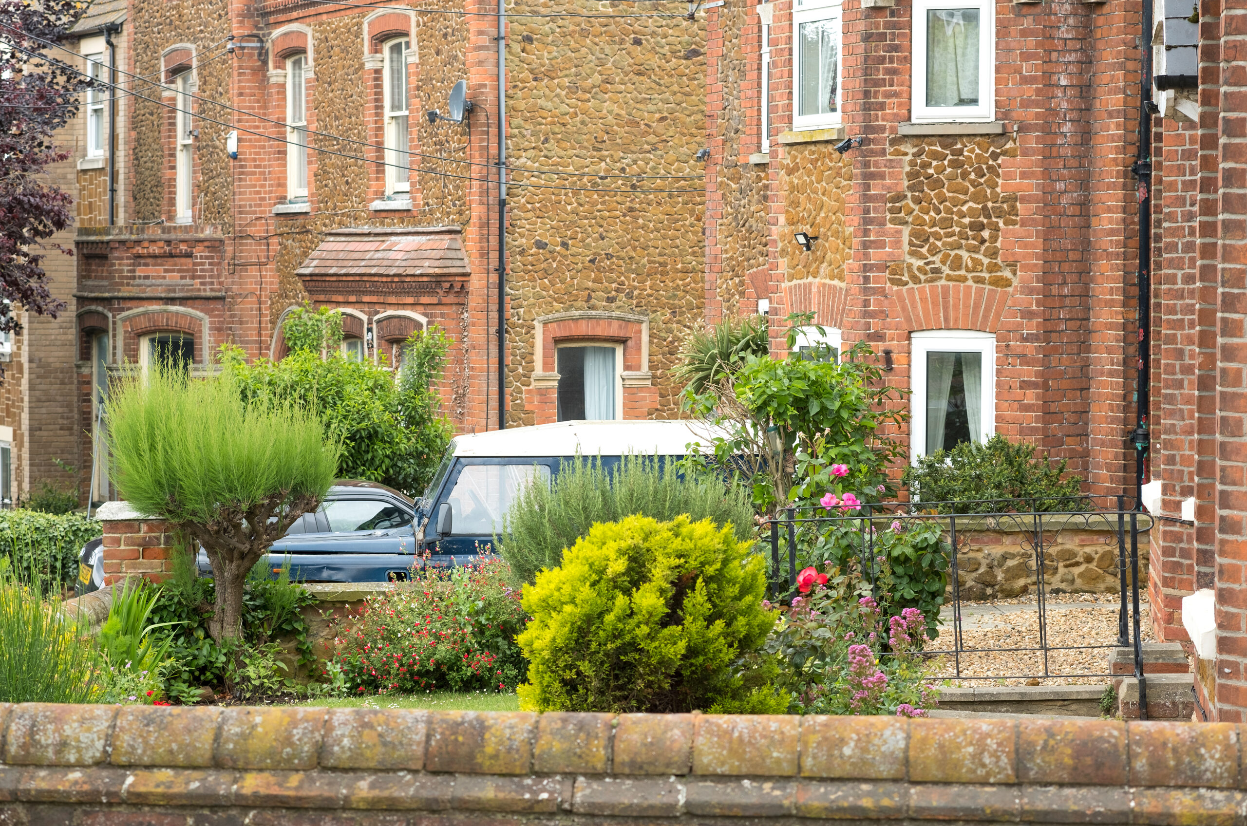 A row of traditional brick residential flats with green front gardens, representing UK properties that may require a lease extension valuation.